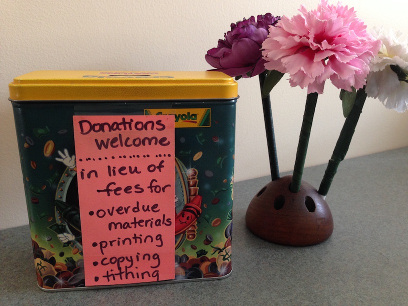 Tin donation box with handwritten note and paper flowers